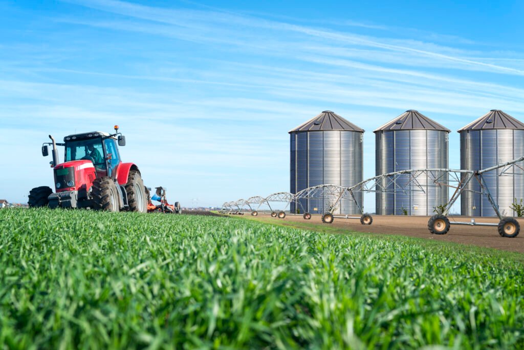 agriculture and food production concept with tractor machine silos and irrigation system.